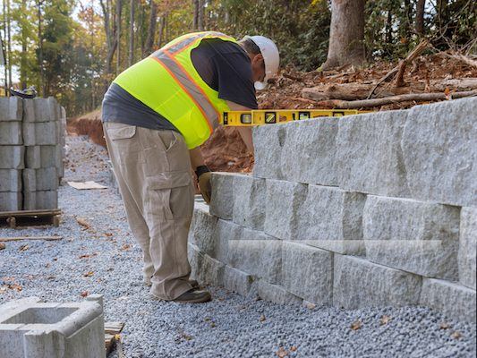 Crew member measuring a concrete block retaining wall under construction in Gwinnett County, GA