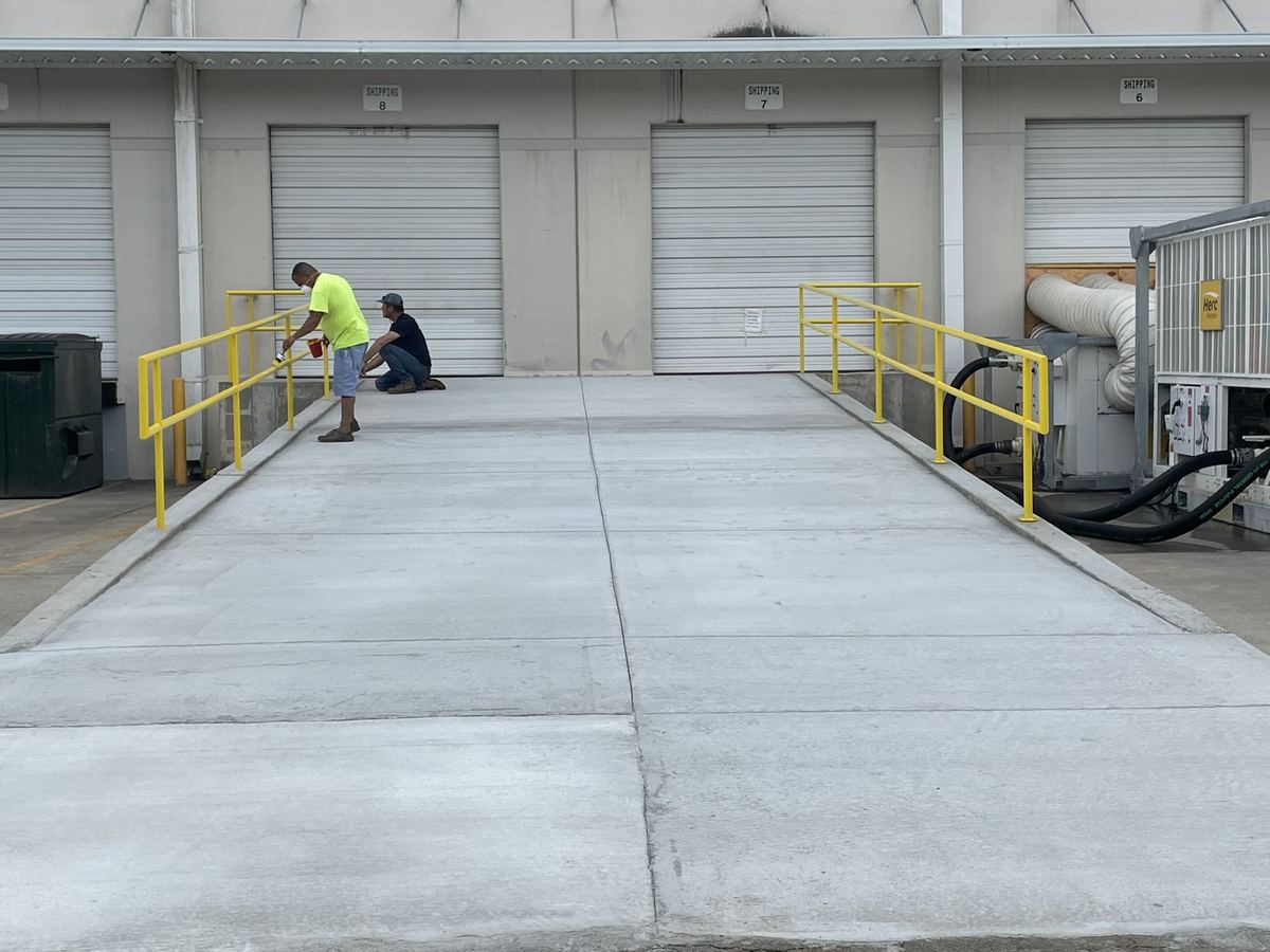 Crew finishing a concrete loading ramp with yellow safety rails at a commercial building in Gwinnett County, GA