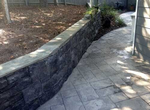 Stamped concrete walkway next to a dark block retaining wall with a cap in Gwinnett County, GA