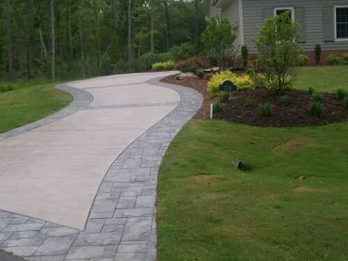 Curved concrete path with a gray stamped stone-pattern border through a green lawn in Gwinnett County, GA