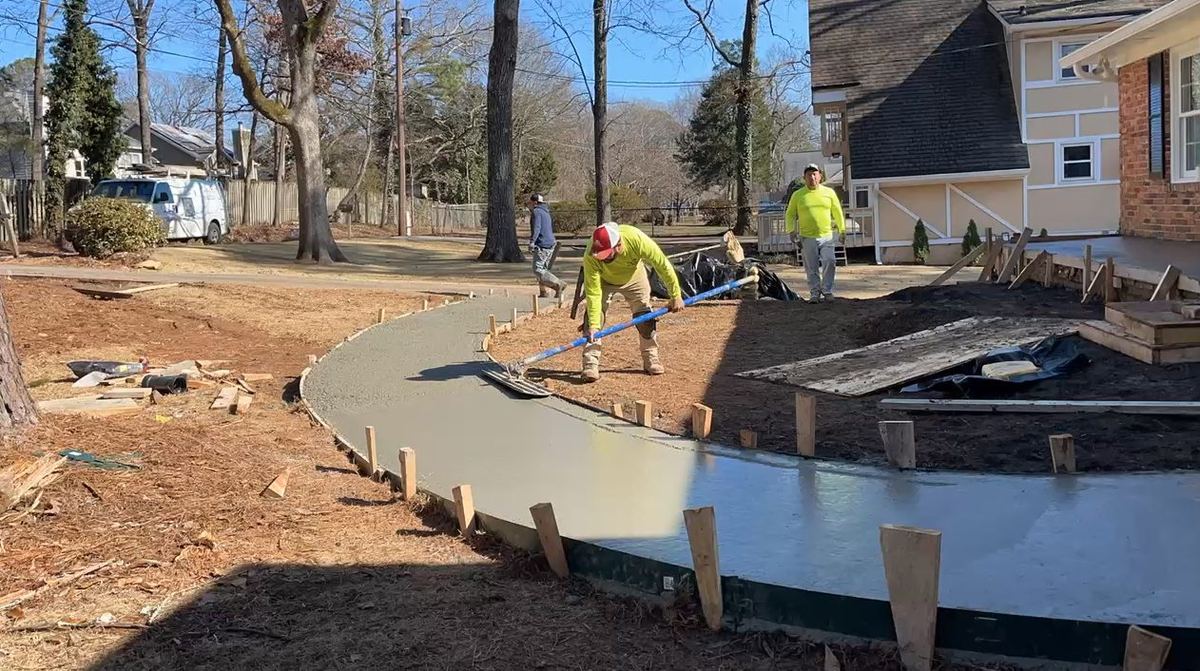 Crew screeding a freshly poured curved concrete walkway inside wood forms in Gwinnett County, GA